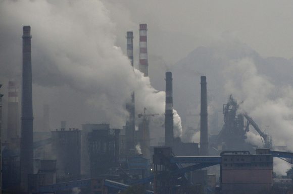 Smoke rises from chimneys and facilities of steel plants on a hazy day in Benxi